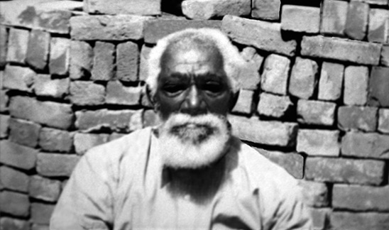 American slave man, seated near brick wall